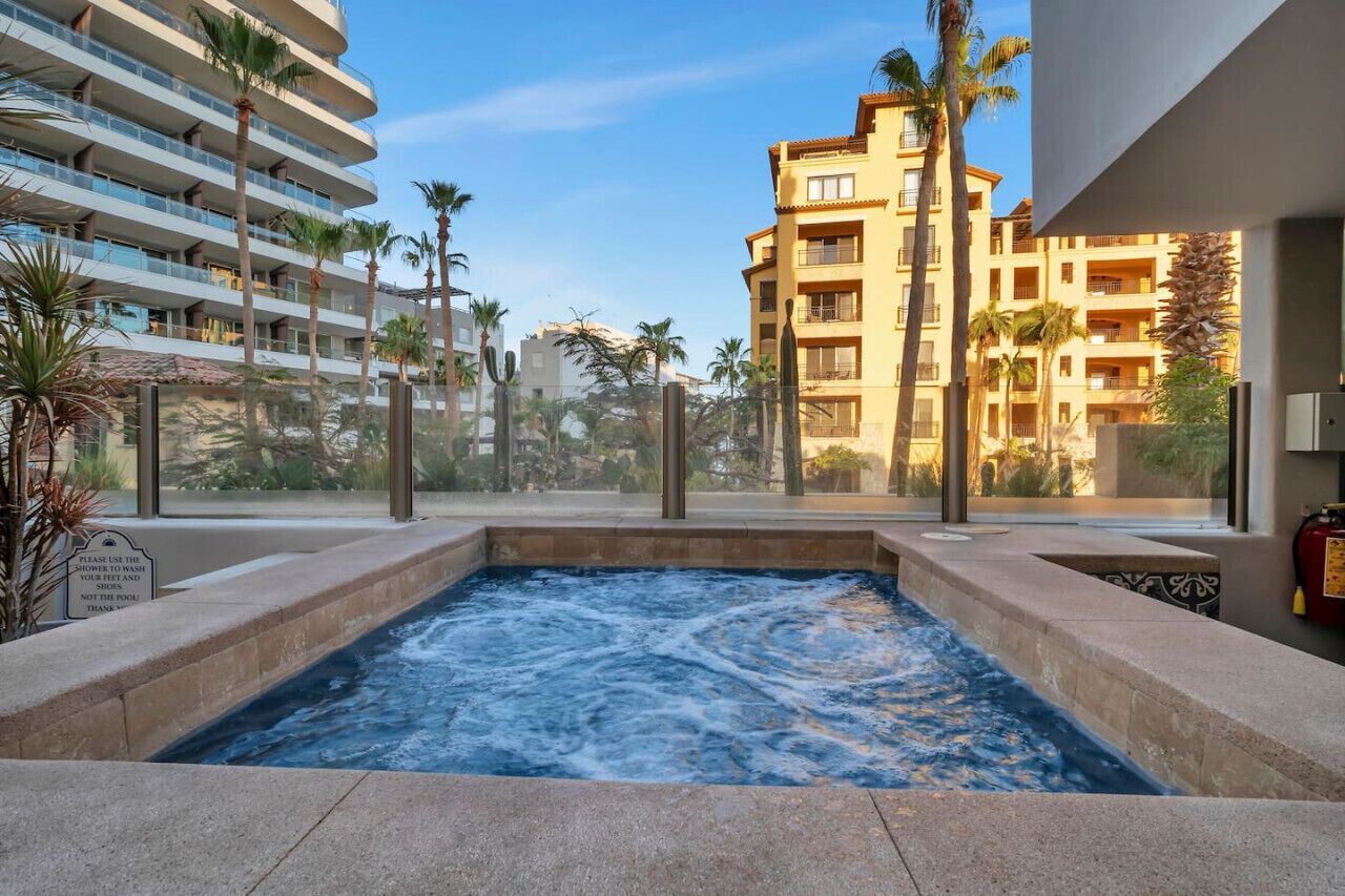 A hot tub area with a view of surrounding buildings, palm trees, and a clear sky.
