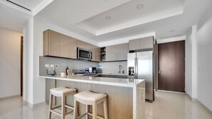 A modern kitchen with a central island, stainless steel appliances, and light wood cabinetry.
