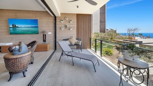 A balcony with a view of the sea, a ceiling fan, and a seating area with a table and chairs. - Ocean View, Overlooking Quivira, Infinity Pool (Cabo San Lucas)