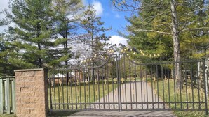 A gated entrance with a stone wall and a metal gate. - Lakeview private suite with kitchen (Twin or King) (Loretto)