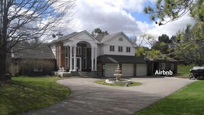A large, two-story house with a driveway leading to a front porch. - Lakeview private suite with kitchen (Twin or King) (Loretto)