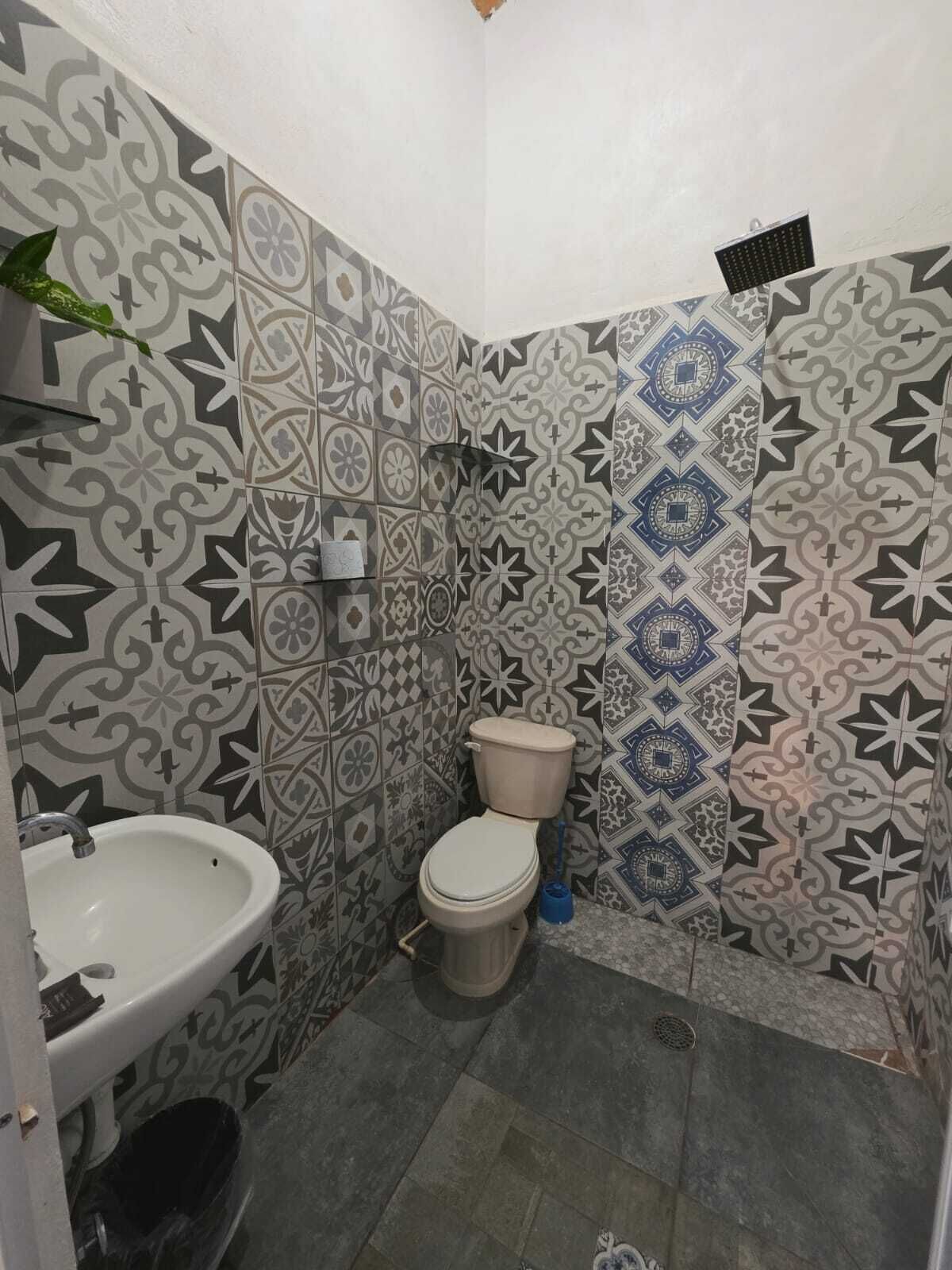 Une salle de bain comprenant des toilettes, un lavabo et un espace douche.