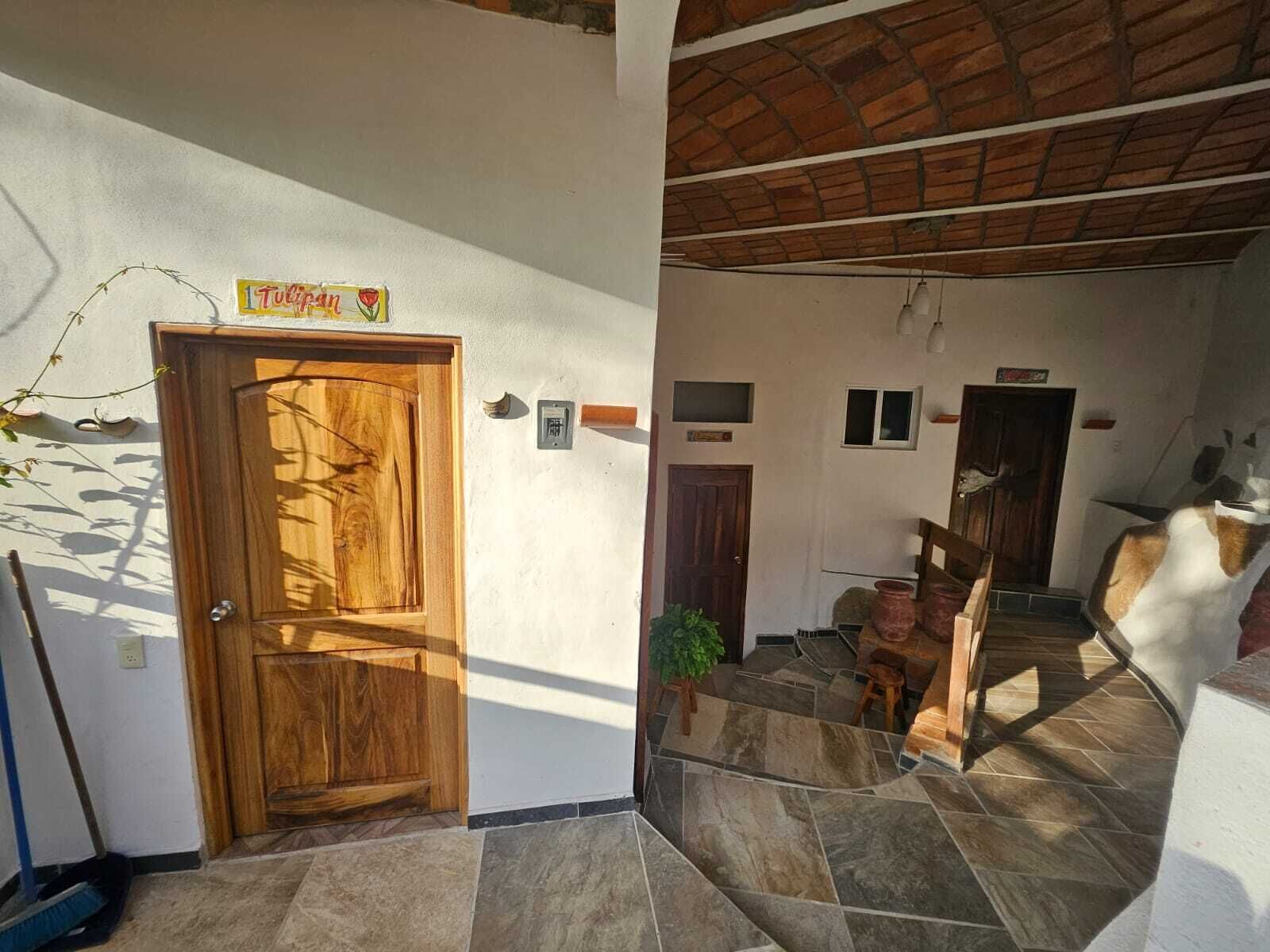 A wooden door with a sign above it, a tiled floor, a brick ceiling, and a small plant in the corner.
