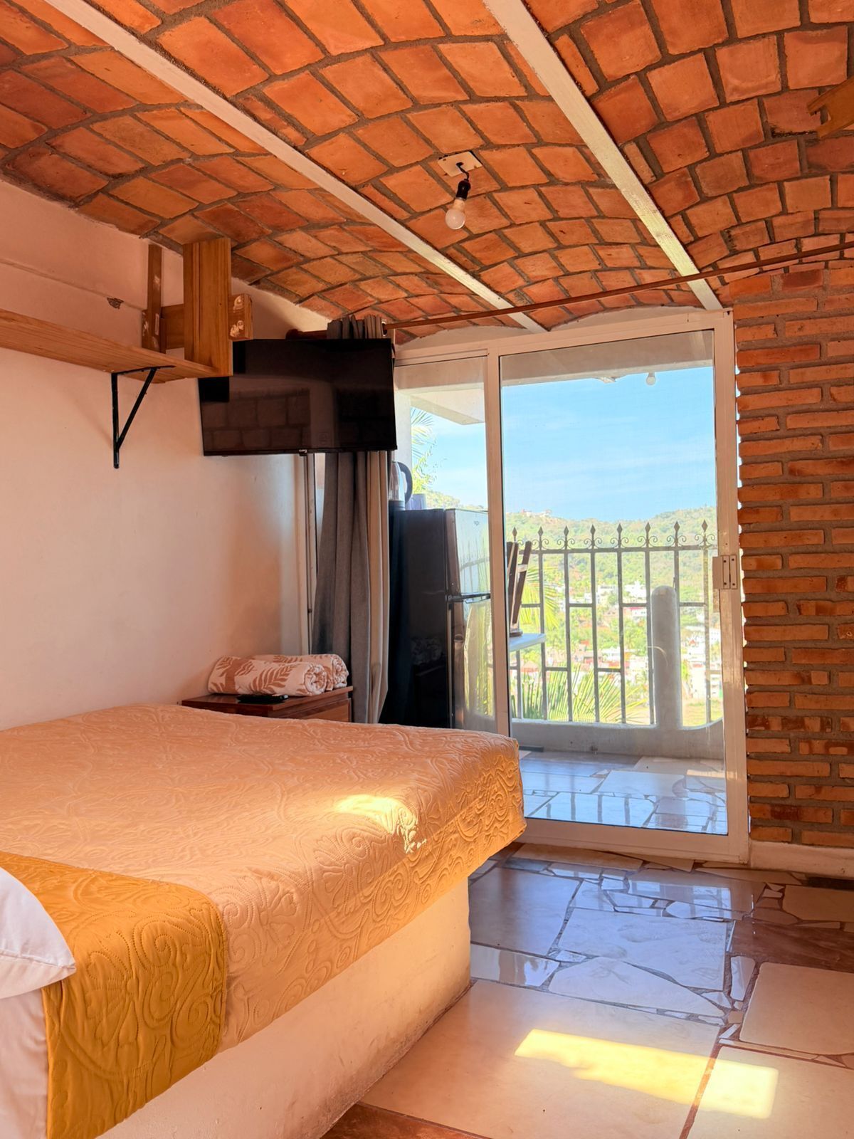 Una habitación con cama, televisión y balcón con vistas.