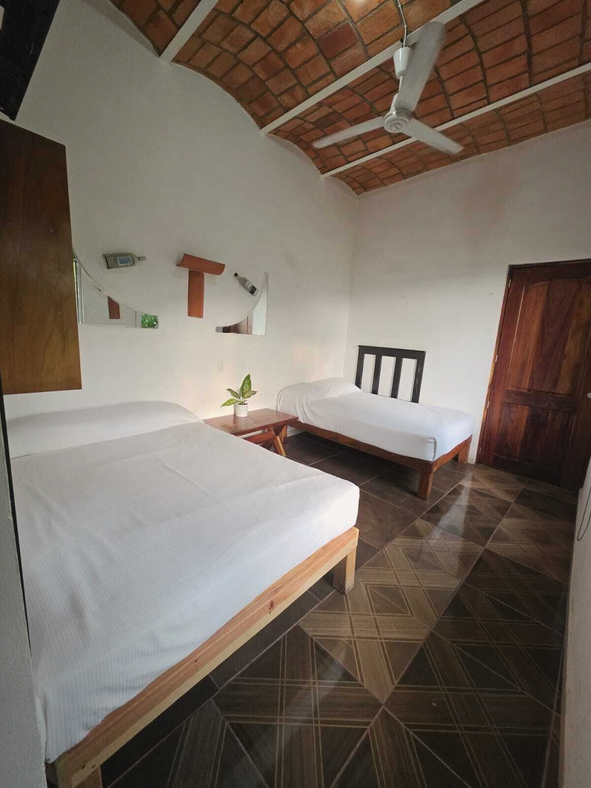 Una habitación con dos camas, un ventilador de techo y piso de baldosas.