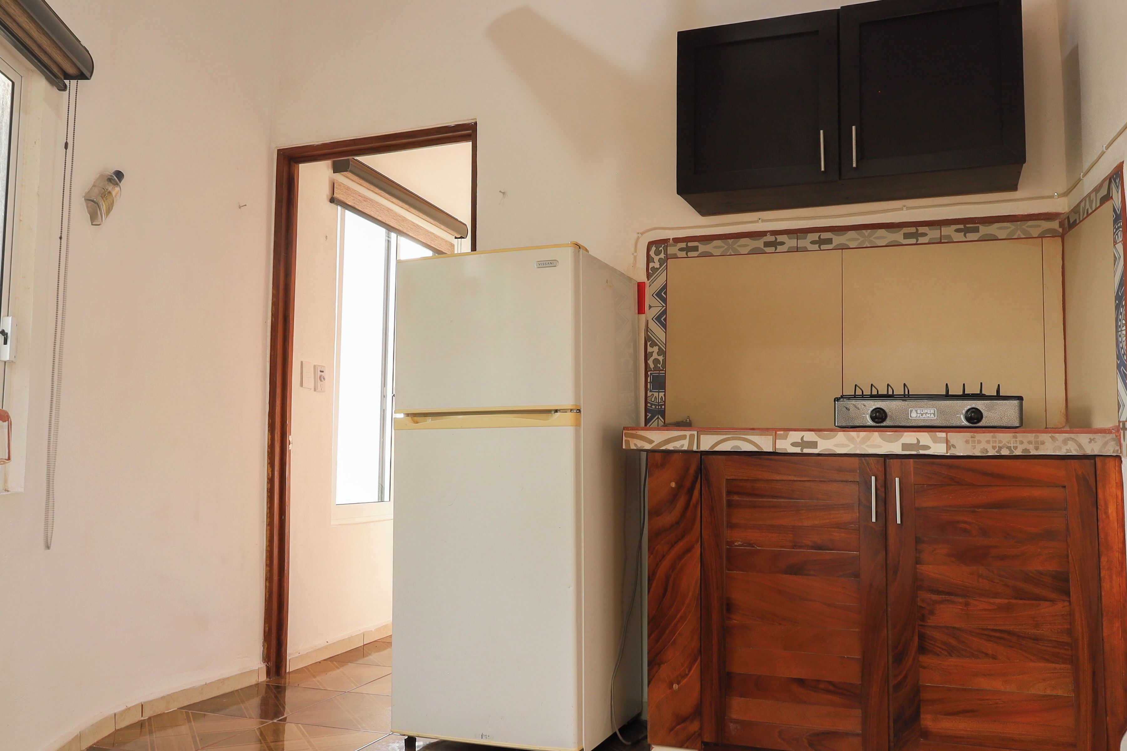 A kitchen with a white refrigerator, wooden cabinets, and a tiled backsplash.