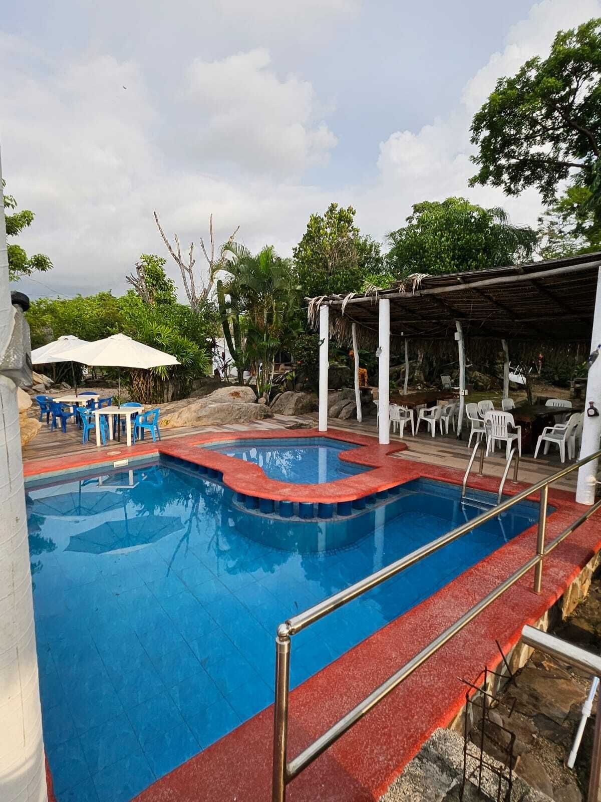 A swimming pool with a red border, surrounded by white lounge chairs and umbrellas.