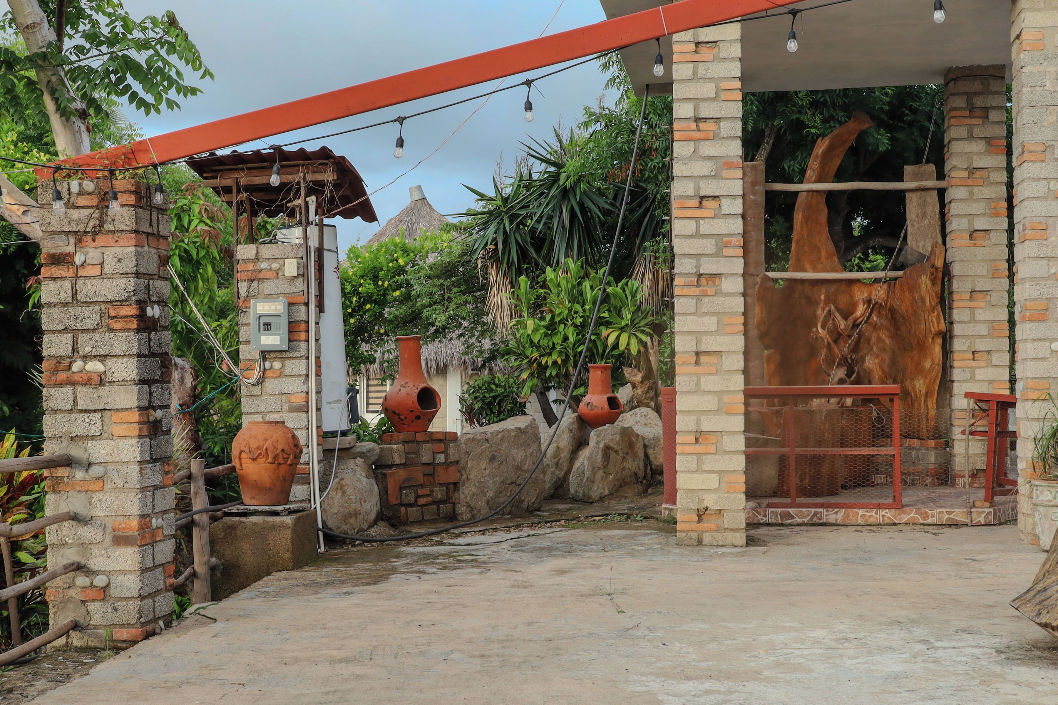 A rustic building with a brick facade, terracotta pots, and a wooden structure with a metal frame.