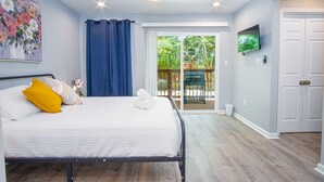 A bedroom with a bed, a ceiling fan, a TV, and a sliding glass door leading to an outdoor area. - Comfortable 4BR 2 5BA Family Home Near Riverwalk (San Antonio)