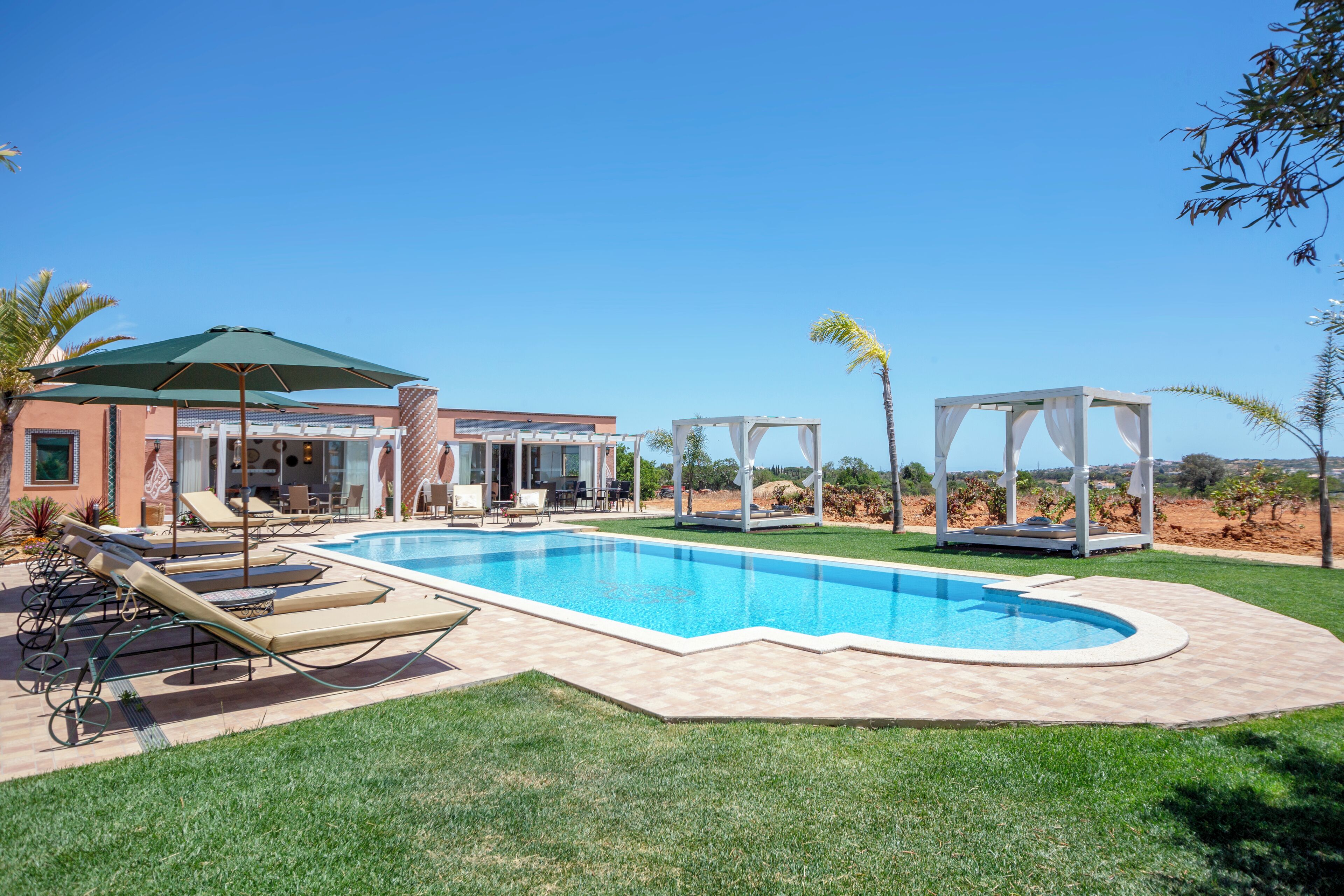 Ein Pool mit Liegestühlen, einer überdachten Sitzgelegenheit und Blick auf die umliegende Landschaft.