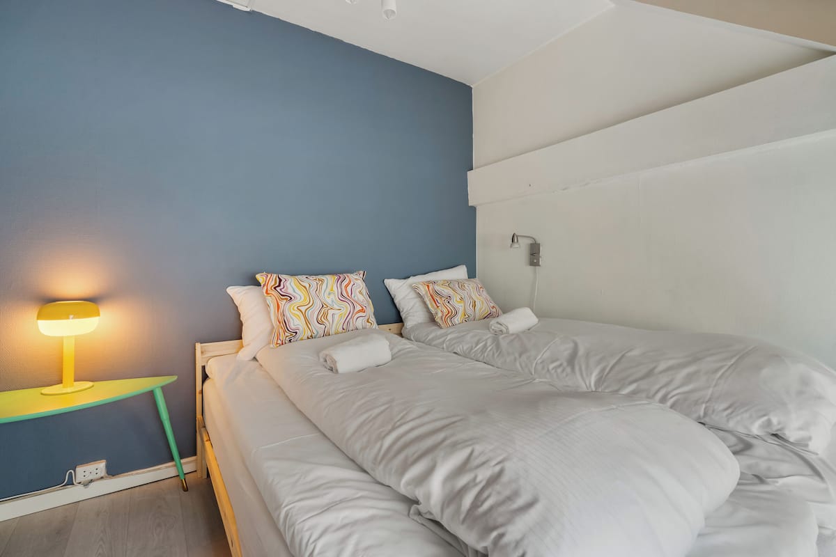 Une chambre à coucher avec un lit, une table de chevet avec une lampe et un luminaire fixé au mur.
