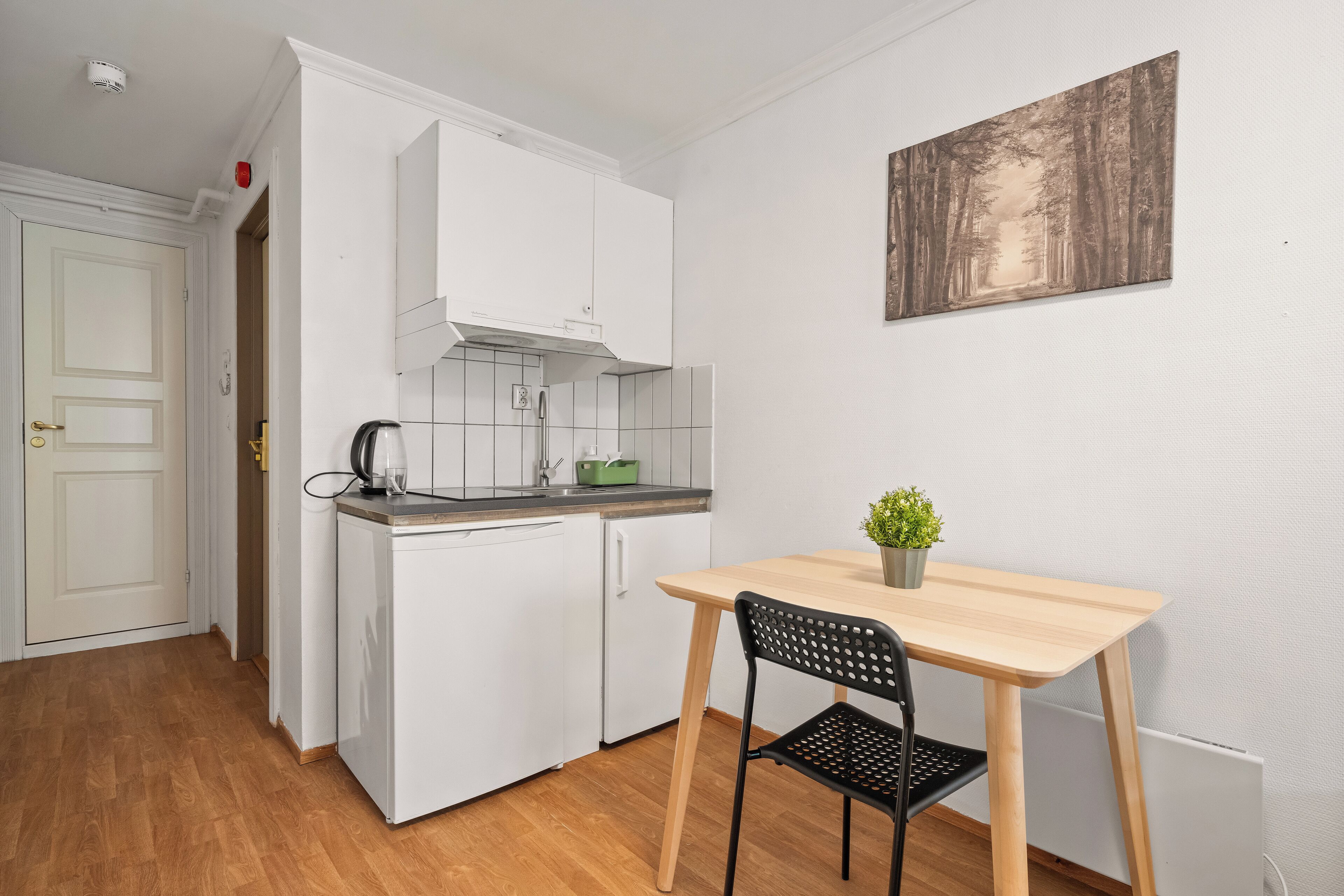 A compact kitchen with white cabinets, a dishwasher, and a small dining table with a chair.