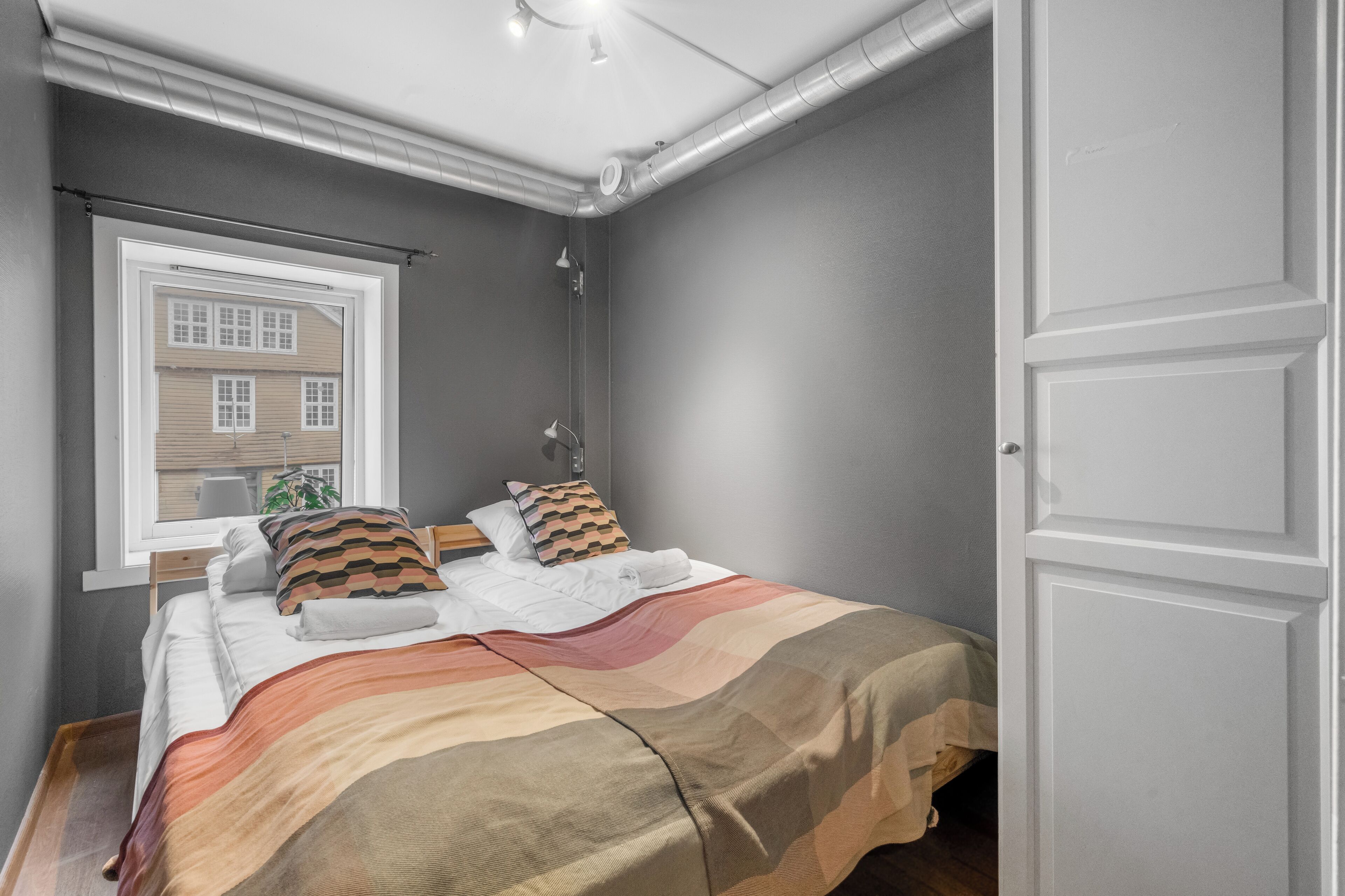 A bedroom with a bed, a window, and a door.