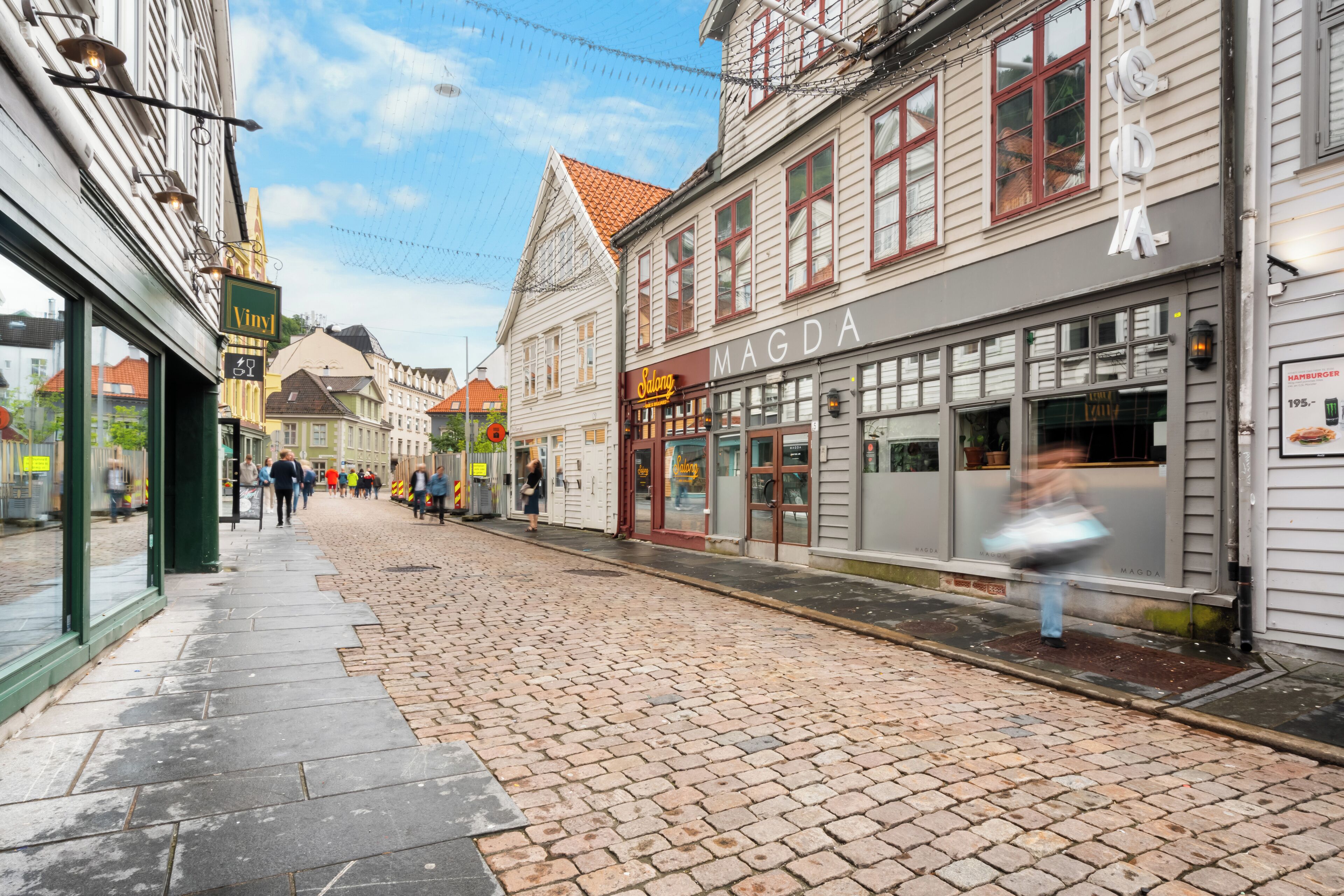 A cobblestone street lined with historic buildings, including a shop with a sign that reads "MAGDA."