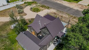 A two-story house with a dark roof, a visible garage, and a driveway leading to the house. - Courtyard Hot Tub in the Heart of Downtown (Panguitch)