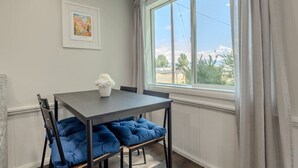 A dining area with a table, chairs, and a window with curtains. - Courtyard Hot Tub in the Heart of Downtown (Panguitch)