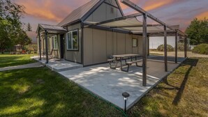 A modern house with a covered patio, a picnic table, and a well-maintained lawn. - Courtyard Hot Tub in the Heart of Downtown (Panguitch)
