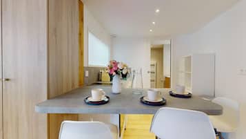 Un espace repas moderne avec une table grise, des chaises blanches et un vase rempli de fleurs.