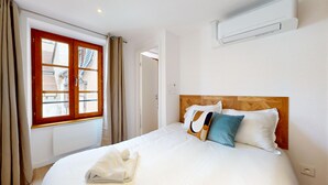Une chambre d’hôtel avec un lit, une fenêtre avec des rideaux, un appareil de climatisation et une porte.