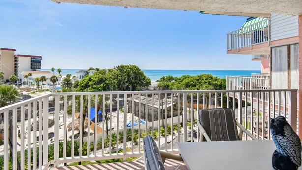 Un balcon avec vue sur la plage et l’océan, une chaise et une table.