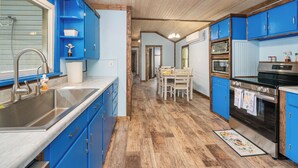 Een keuken met blauwe kastjes, roestvrijstalen apparatuur en een houten vloer.