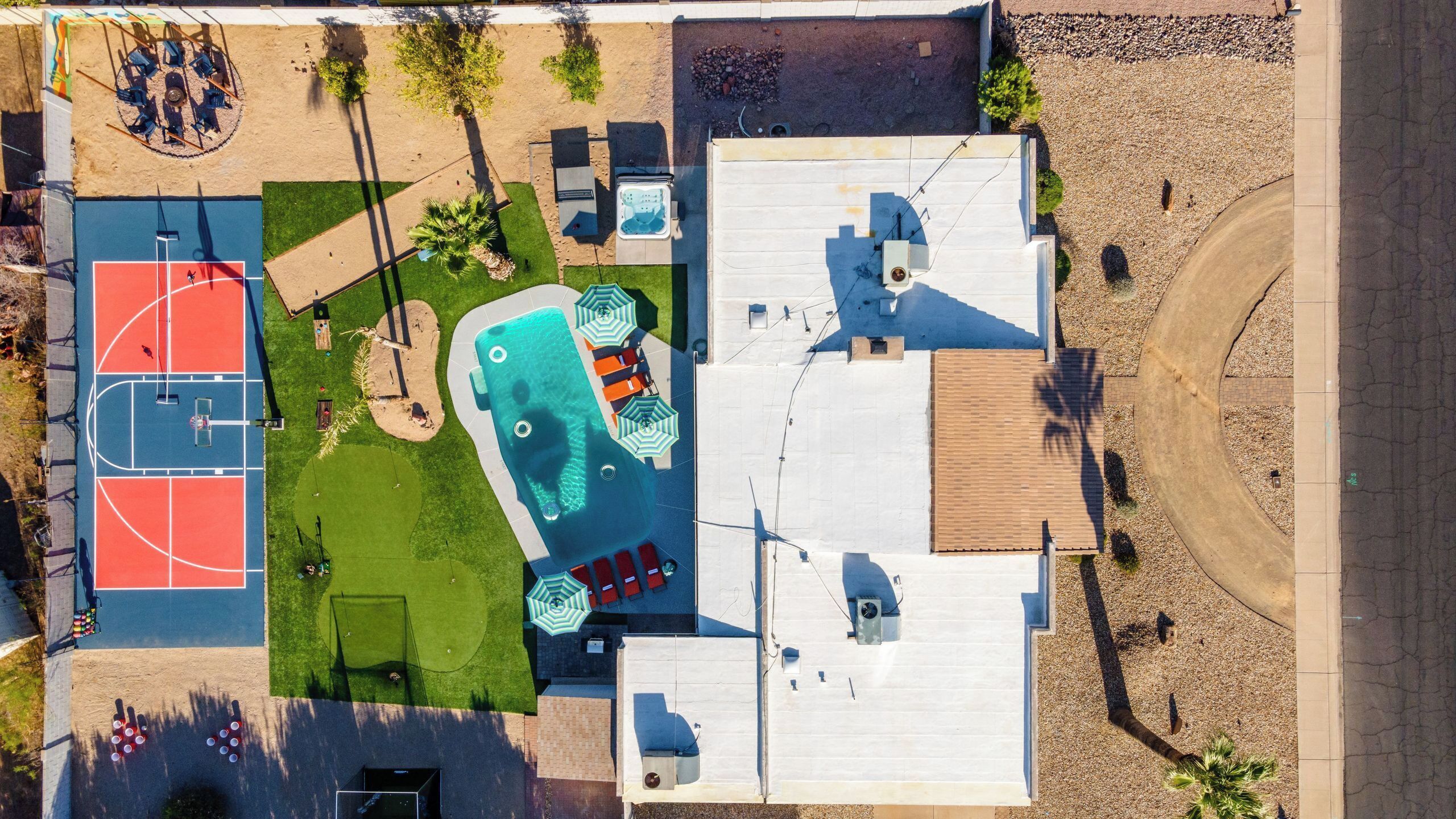 Eine Vogelperspektive eines Wohngebiets mit Tennisplatz, Swimmingpool und überdachter Terrasse.
