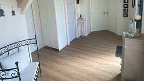A spacious room with a wooden floor, white walls, and a metal bed frame. There are white doors and a small table with a chair. - Renovated house with panoramic view of the bay and the 7 islands  (Perros-Guirec)