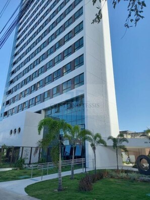 A modern multi-story hotel with a glass facade, a flat roof, and a landscaped entrance with palm trees. - Flats no Parque Shopping por Yolo (Recife)