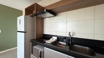 Eine kleine Küche mit Kühlschrank, Herd, Spüle und Holzschränken.