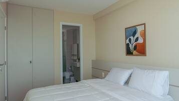 Una habitación de hotel con una cama, un armario y un baño visible a través de una puerta abierta.