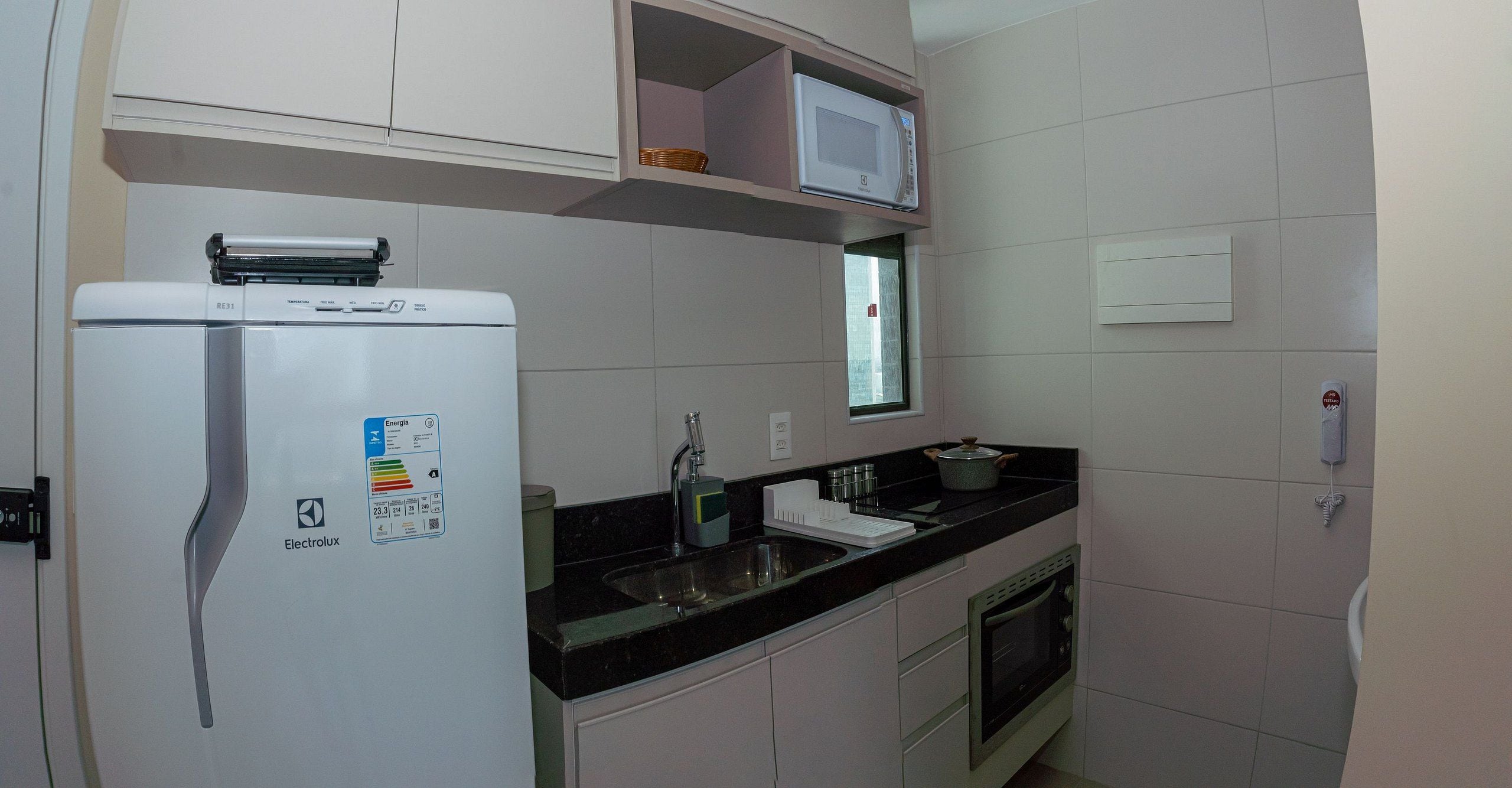 Uma cozinha compacta equipada com frigorífico, micro-ondas, pia e forno.