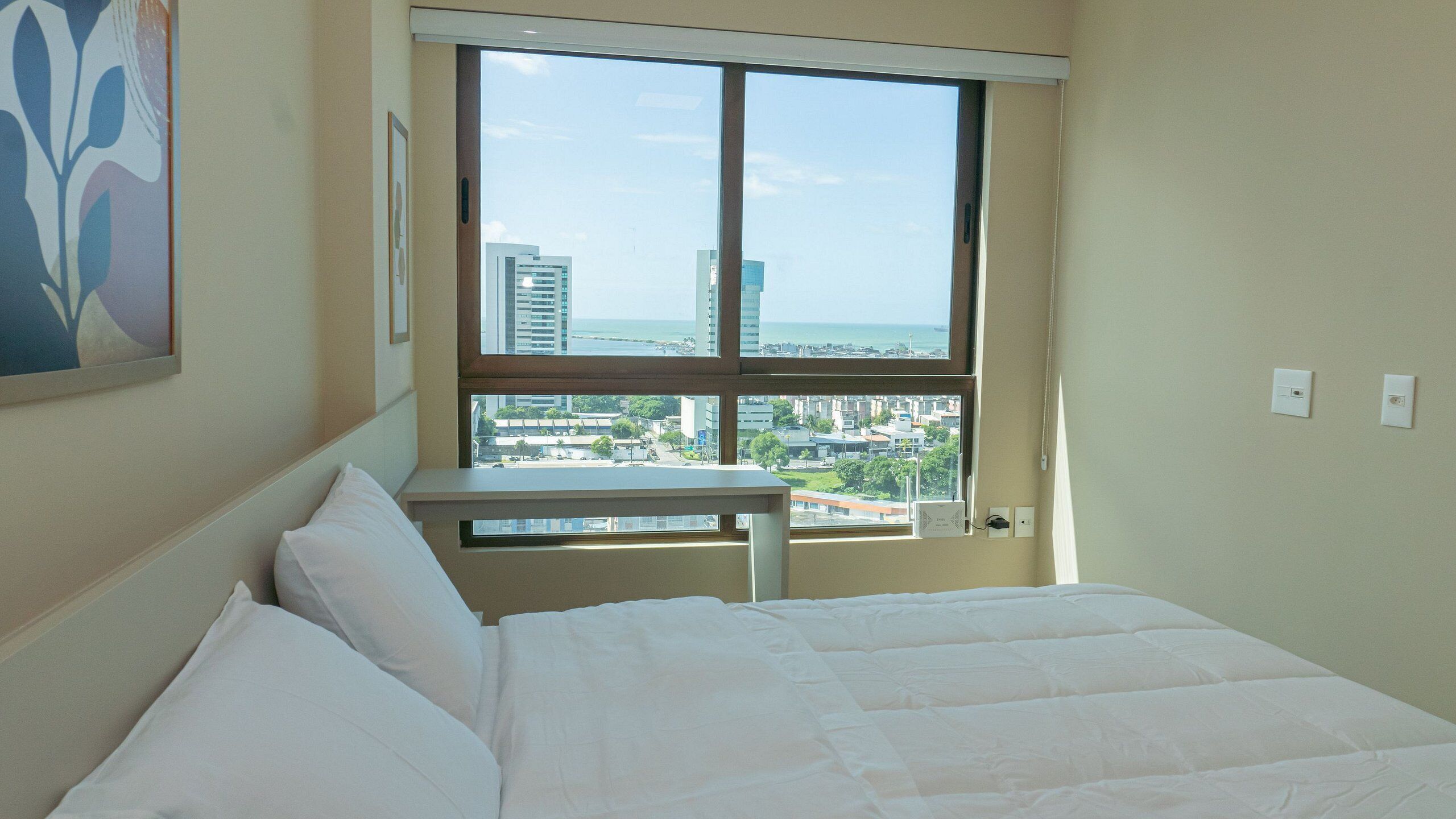 Habitación de hotel con una cama, una mesita y una ventana con vistas a la ciudad.