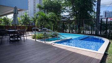 Relax by the pool surrounded by a wooden deck and trees.