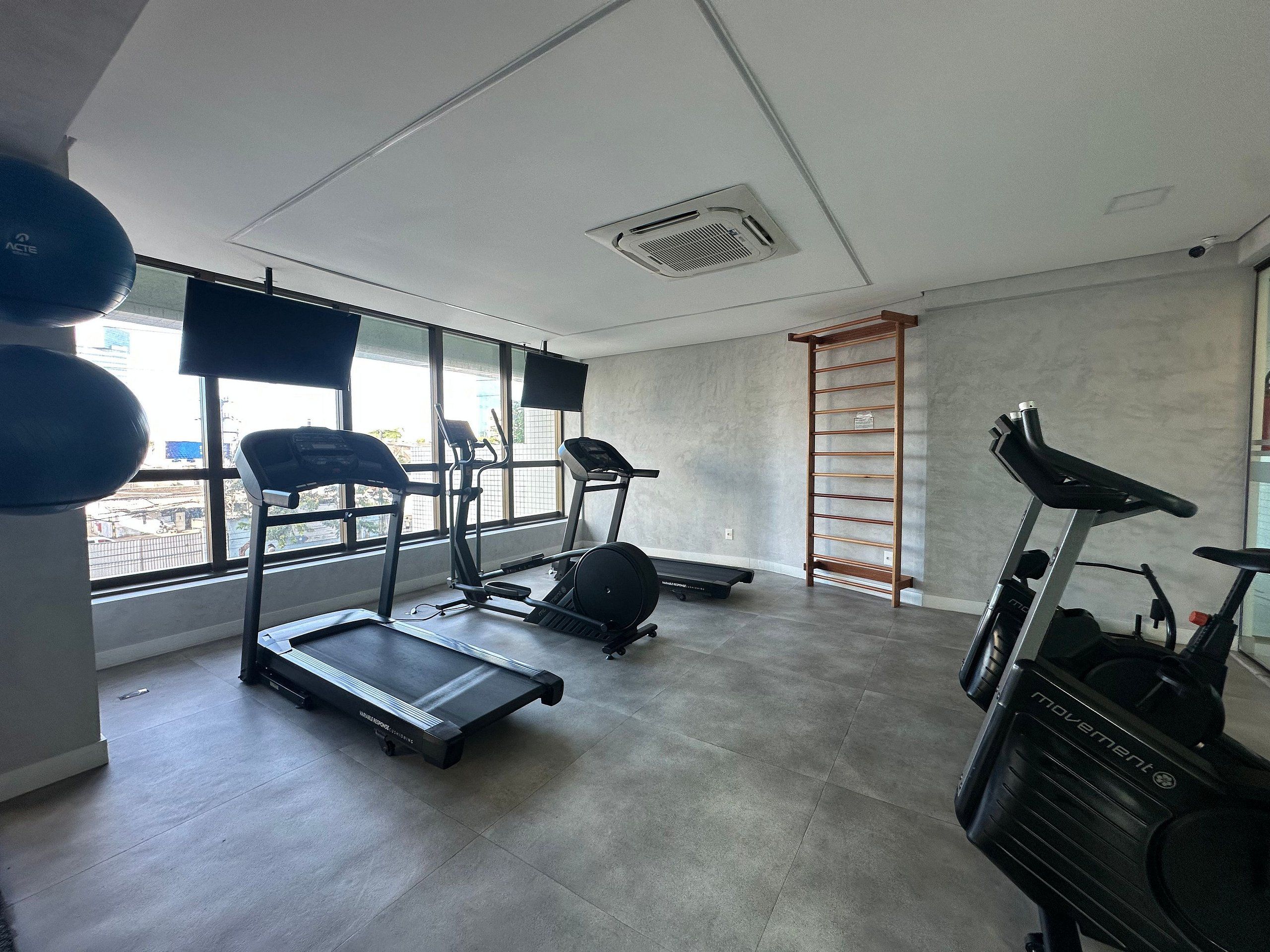 Une salle de sport équipée de tapis de course, d’un vélo d’appartement et d’un porte-haltères fixé au mur.
