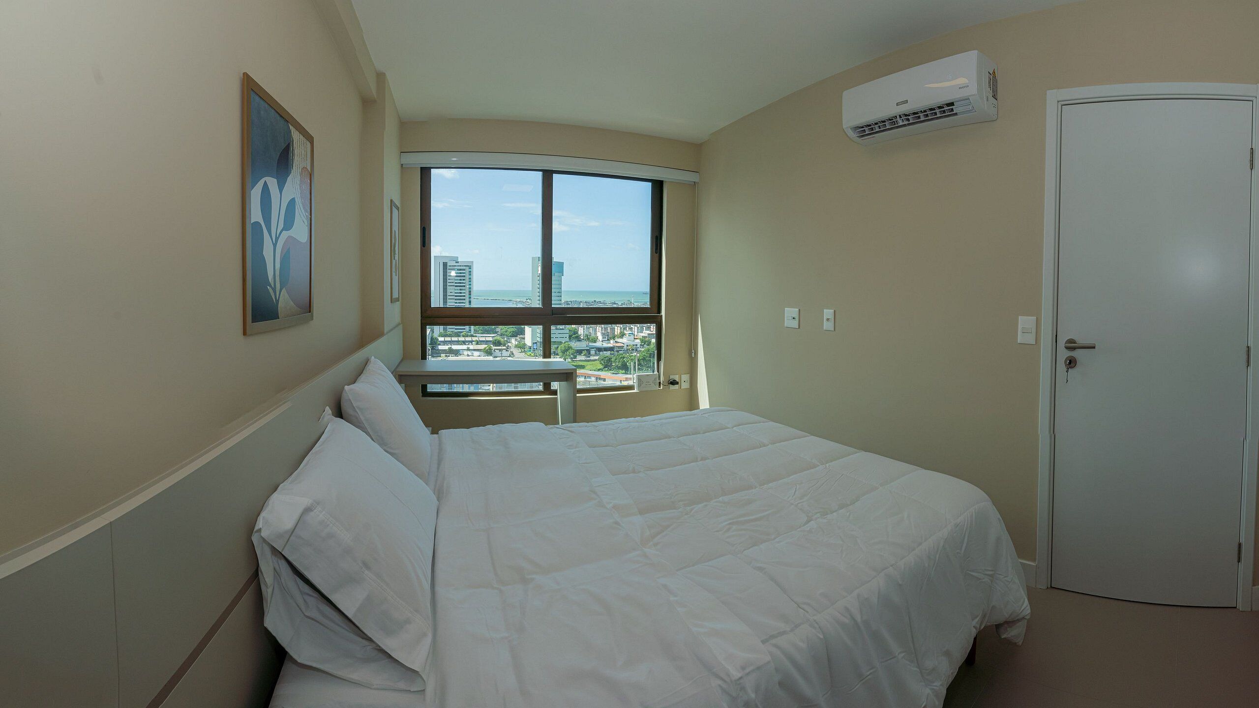 Quarto de hotel com cama, janela vista da cidade, ar condicionado e porta.