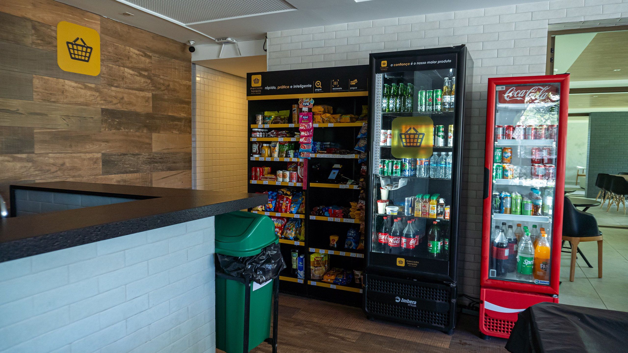 A self-service kiosk area with a Coca-Cola refrigerator and a beverage dispenser.