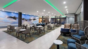 A modern lounge area with seating arrangements, a patterned carpet, and a mural of airplanes on the wall.