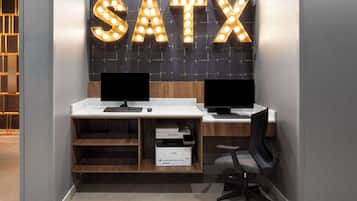 A modern office space with two desks, each with a computer monitor, a keyboard, and a printer.