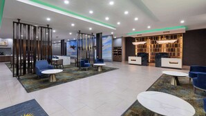 A modern lobby with seating areas, a reception desk, and a decorative wall.