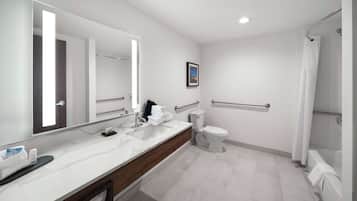 A modern bathroom with a large mirror, white sink, and a shower area.
