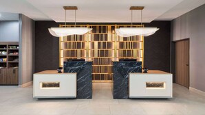 A reception area with marble counters, a herringbone-patterned wall, and a green-lit ceiling.