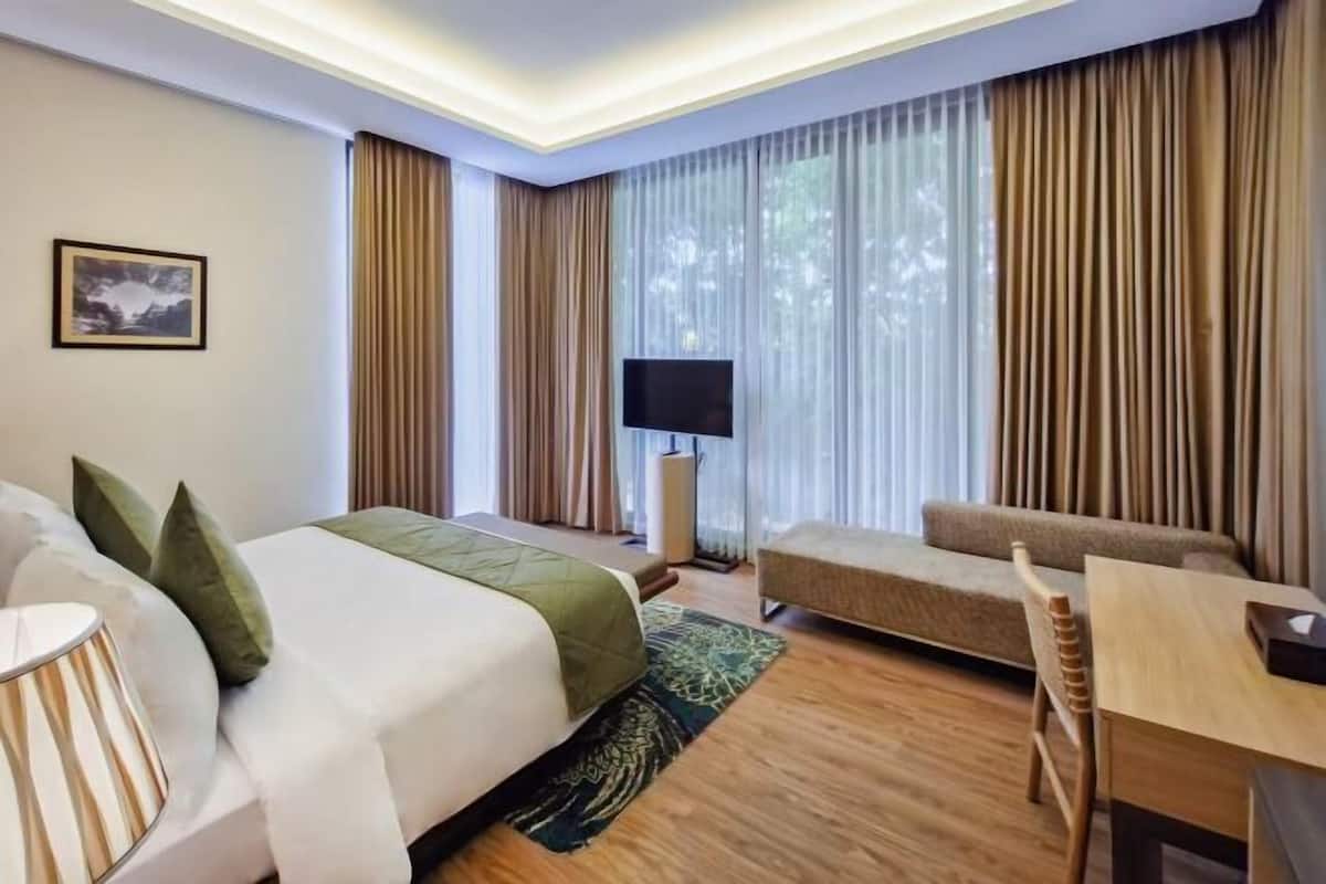 Una habitación de hotel con una cama, un sofá, un escritorio y un televisor.