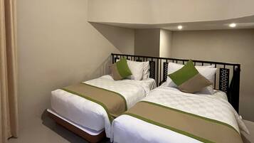 A hotel room with two single beds, beige walls, and a curved ceiling.