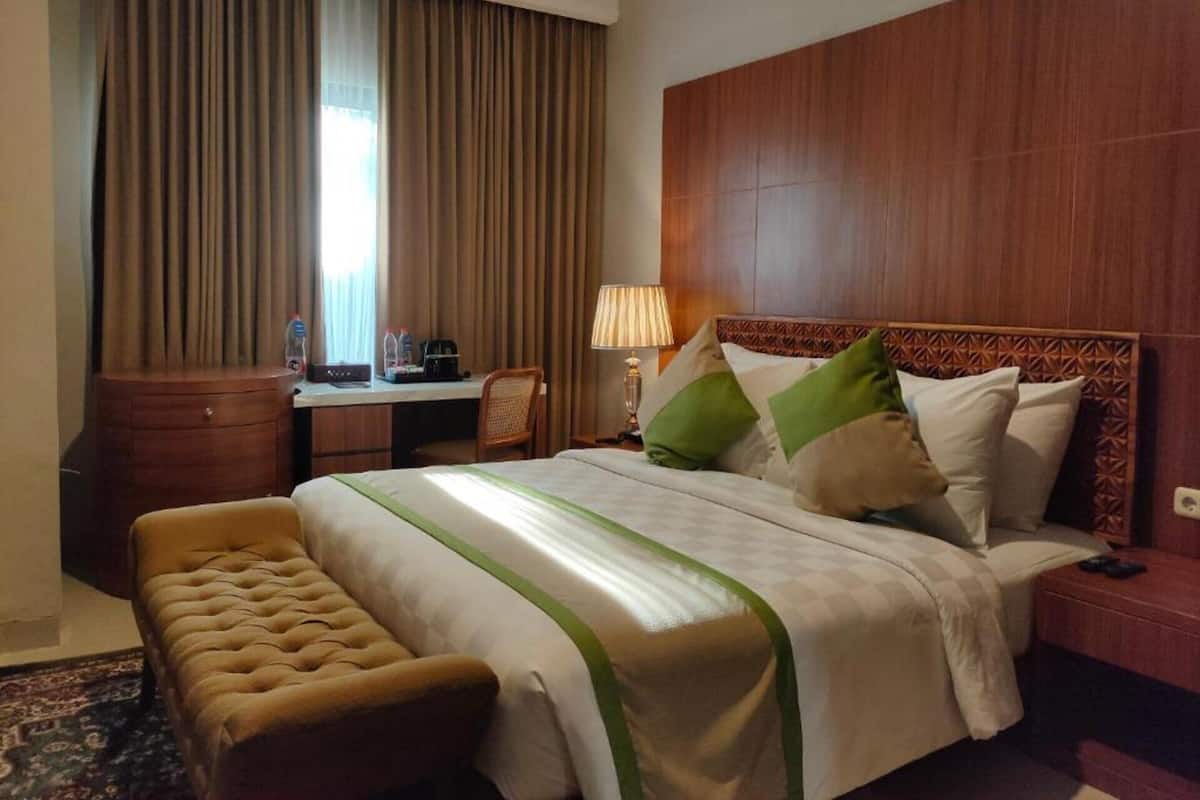 Una habitación de hotel con una cama grande, un escritorio, una silla, una lámpara y un banco.