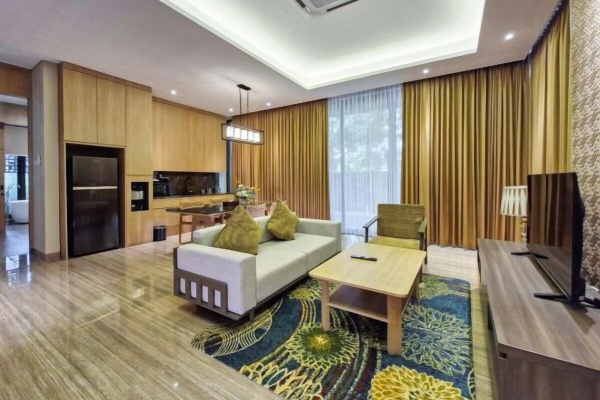 Ein modernes Hotelzimmer mit Sofa, Couchtisch, Fernseher und Küchenzeile.