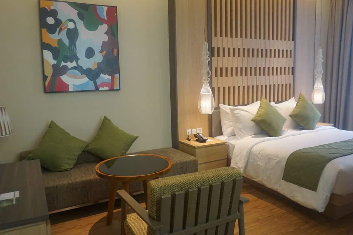 Habitación de hotel con cama, escritorio, silla, sofá y un cuadro en la pared.