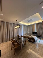 Una sala de estar moderna con una mesa de comedor de vidrio, sofás y un televisor de pantalla plana.