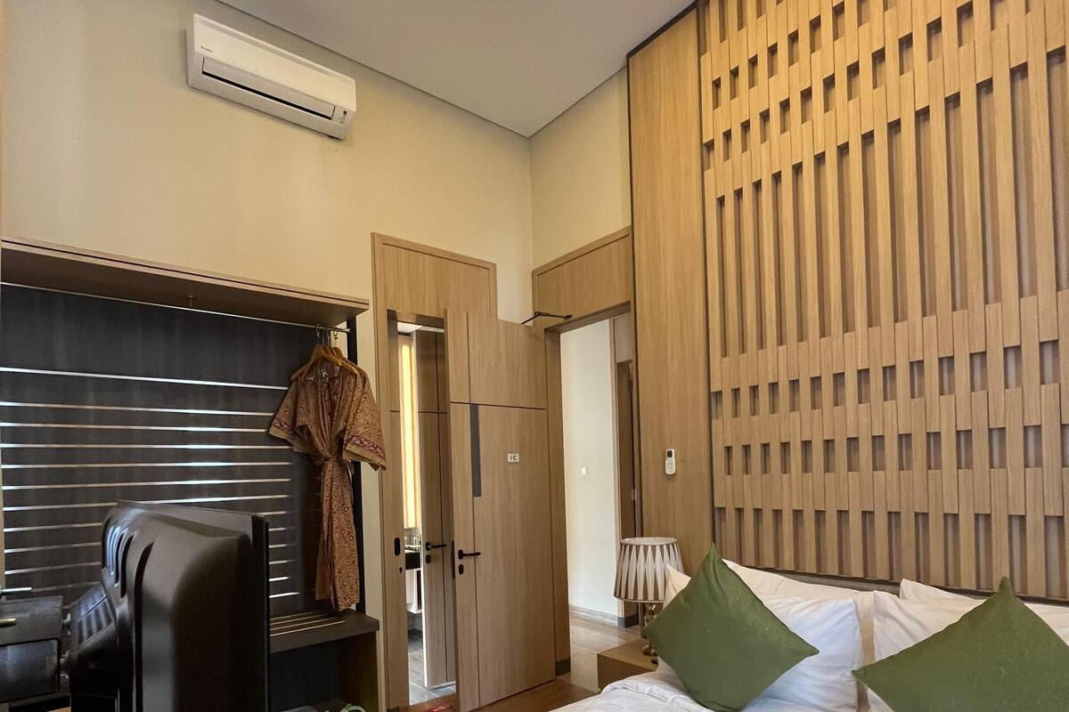 Habitación de hotel con cama, escritorio, silla, aire acondicionado y armario.