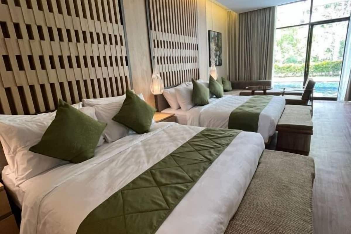 Habitación de hotel con dos camas, cabecera de madera, vistas al exterior y una pequeña mesa.