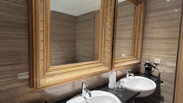 Un baño con dos lavamanos, un espejo grande y un dispensador de toallas.